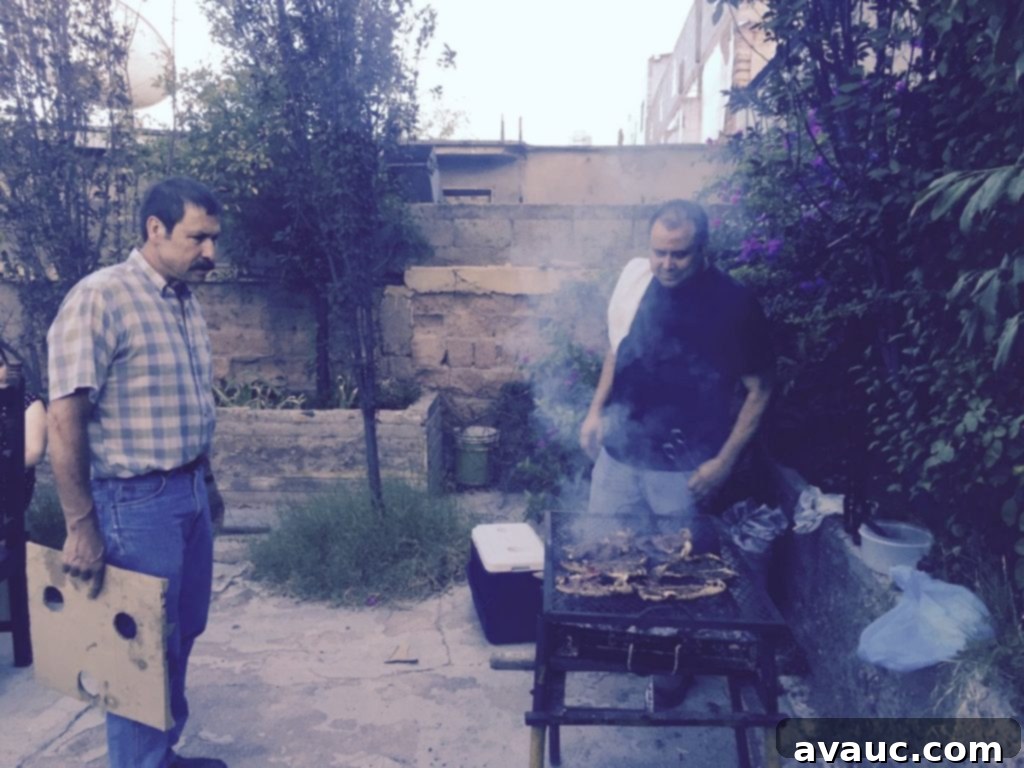 Two men grilling various meats over an open flame at a parrillada, surrounded by family.
