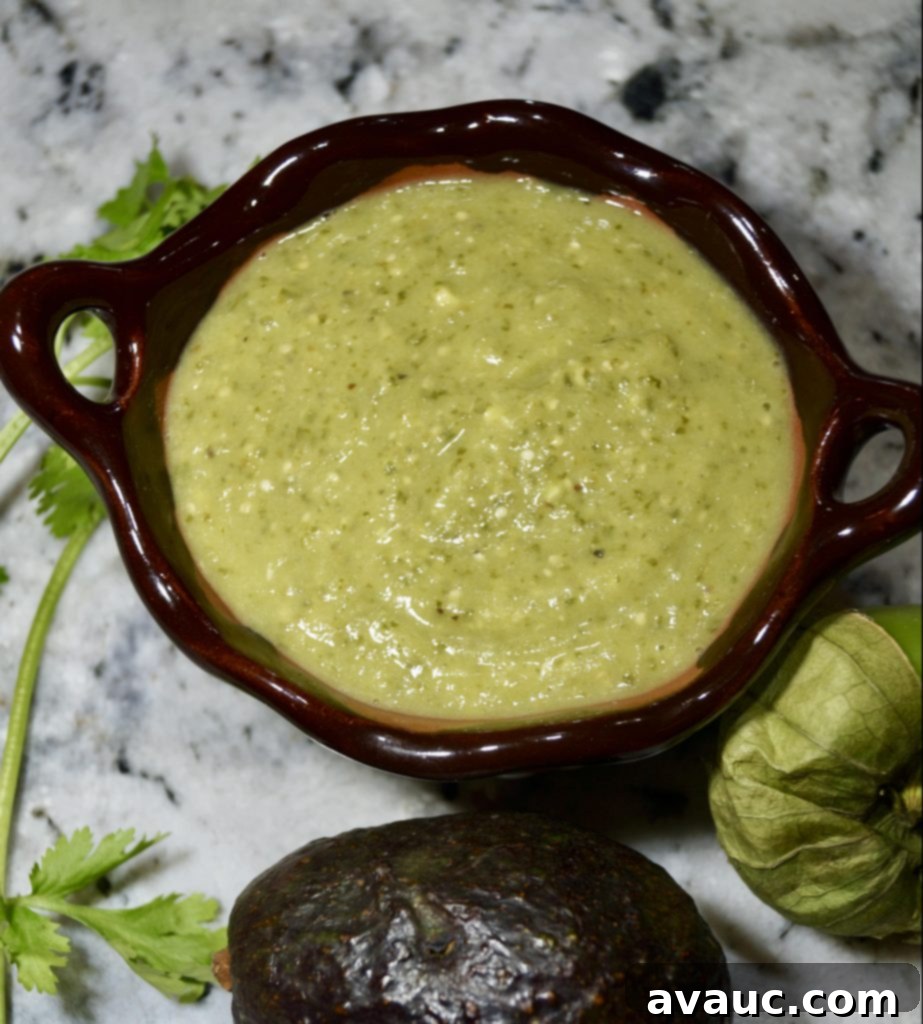 Smooth and creamy green tomatillo avocado salsa in a white bowl, garnished with cilantro.