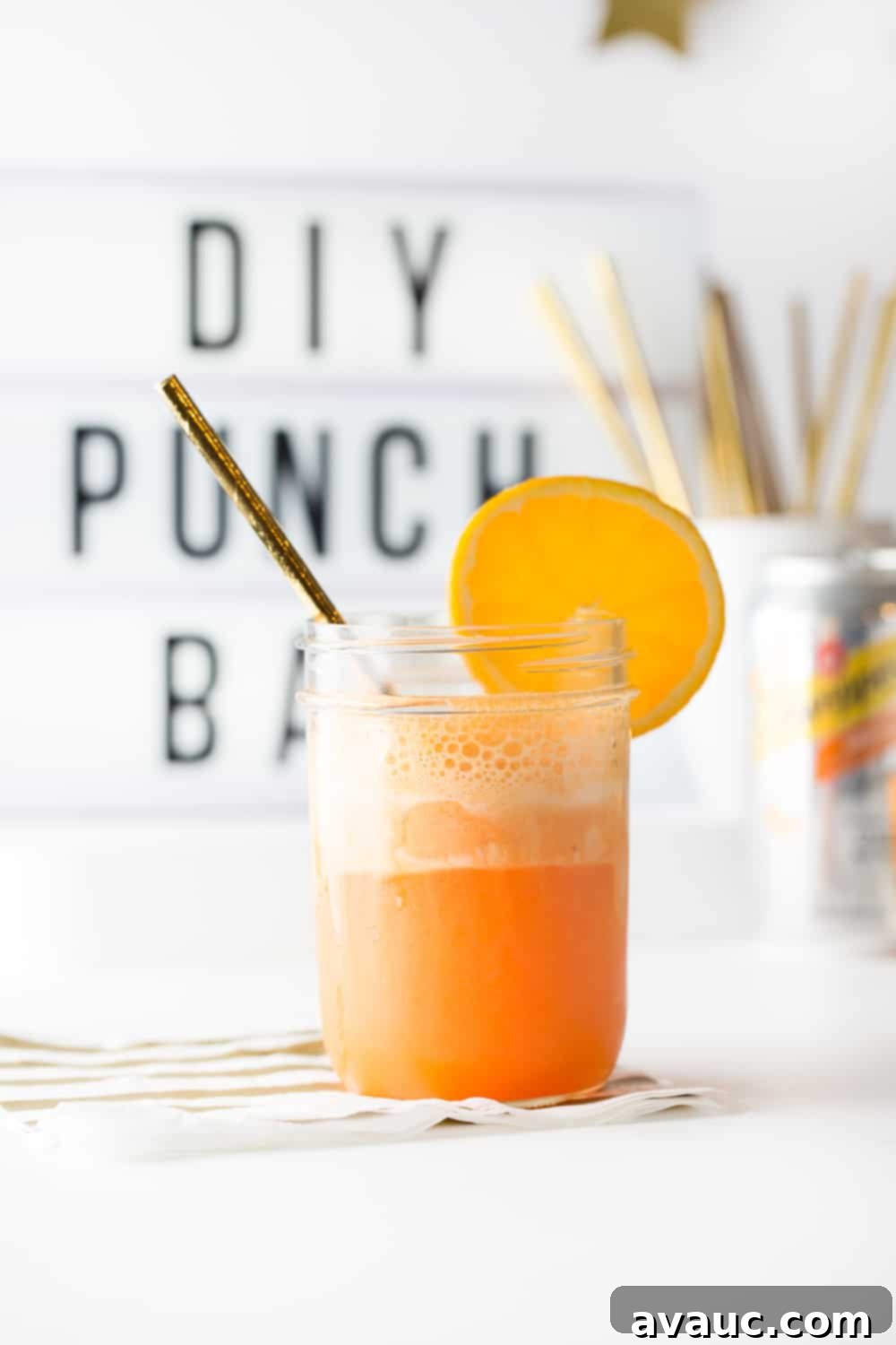 Another view of a glass of carbonated, fizzing orange sherbet punch with an orange slice, emphasizing its refreshing appeal.