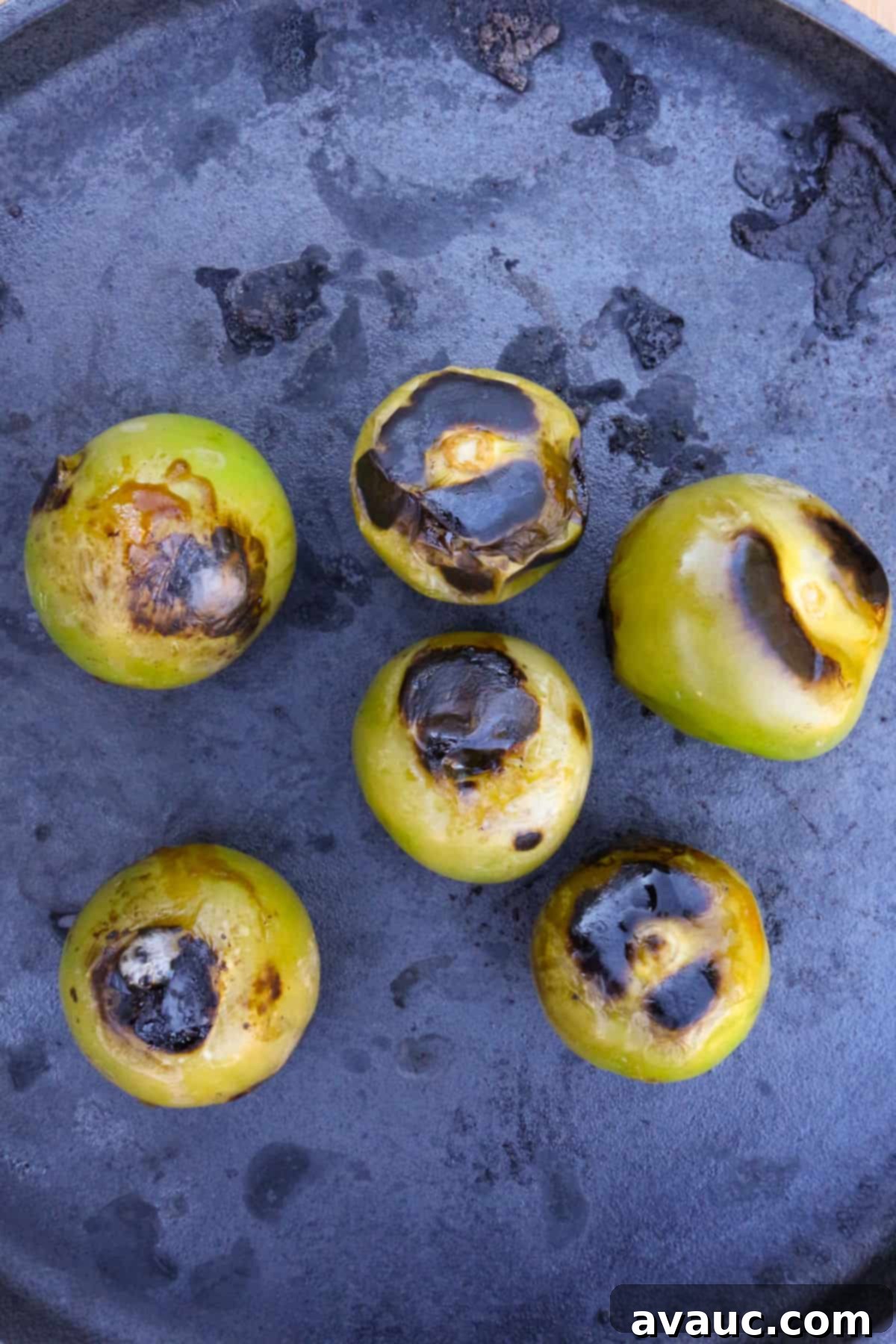 Charred tomatillos on a cast-iron comal.