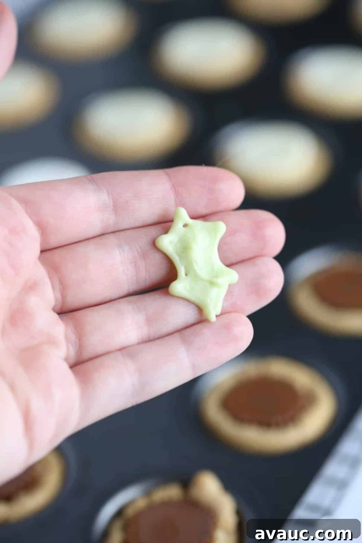 Holly Jolly Cookie Cups 7 Hand holding white chocolate green holly leaf to make Holly leaf printable template to make easy Christmas holly cookie cups!
