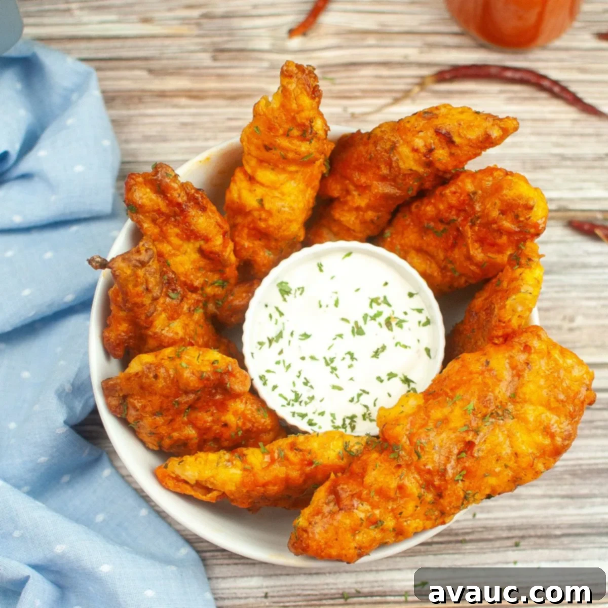 A serving bowl of air fried buffalo chicken tenders, garnished with fresh herbs and ready for dipping.