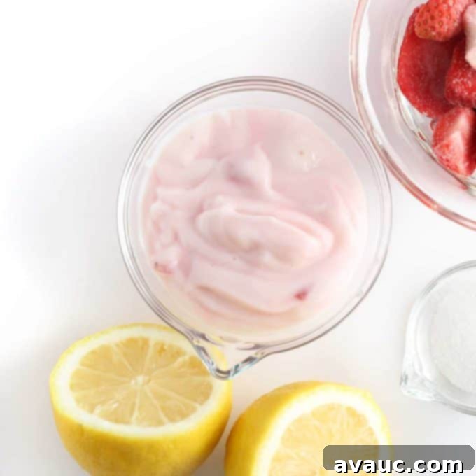 Bowl of raspberry yogurt with lemon and strawberries