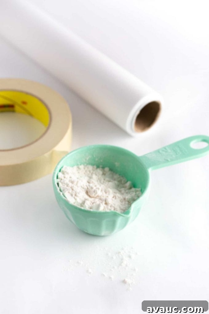 Materials for Roll Out Sugar Cookies - Measuring cup of flour, roll of parchment paper, and masking tape