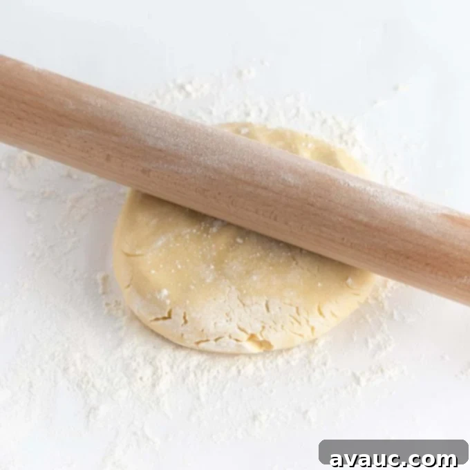Mastering Flawless Cut Out Sugar Cookies 12 Sugar cookie dough being rolled out smoothly with a guided rolling pin on parchment paper