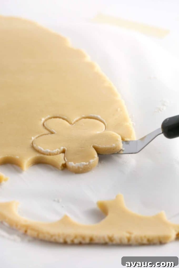 Mastering Flawless Cut Out Sugar Cookies 16 Lifting a cut flower sugar cookie dough shape off of parchment paper using an offset spatula