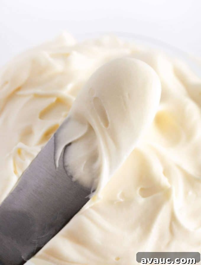 Spatula of vanilla cream cheese frosting for cookies, showing fluffy texture