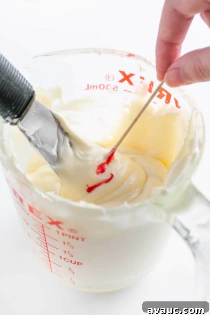 Adding red food coloring with toothpick to cream cheese frosting for cookies for a light pink shade