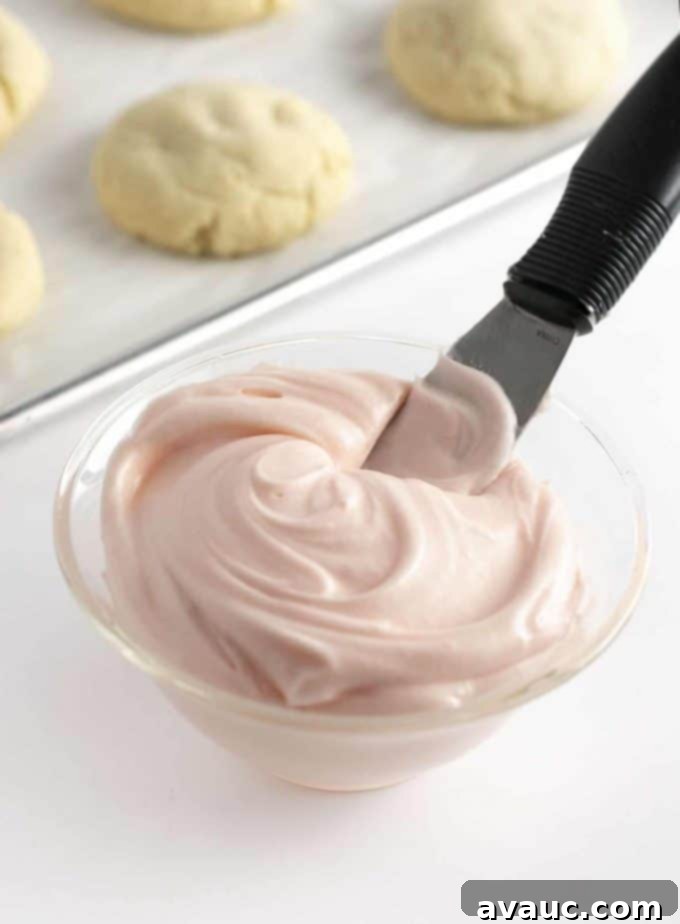 Bowl of vibrant pink cream cheese frosting for cookies