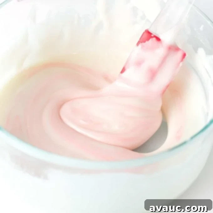 Stirring pink icing with a spatula