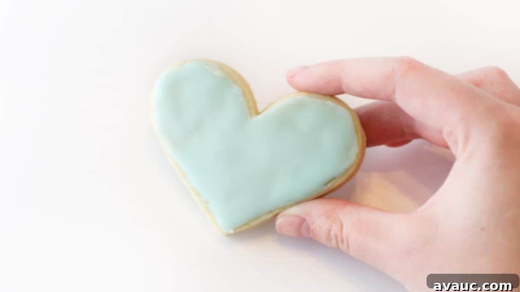 Hand holding a light blue heart sugar cookie
