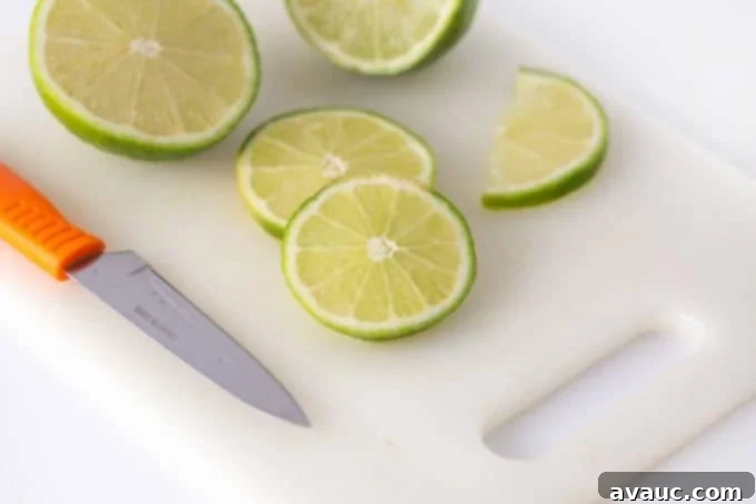 Ingredients for lime sherbet punch laid out on a table: lime sherbet, lemon lime soda, pineapple juice, and fresh limes.