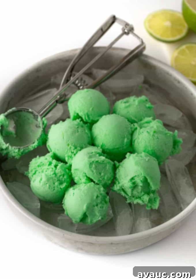 Hands scooping lime sherbet into a punch bowl.