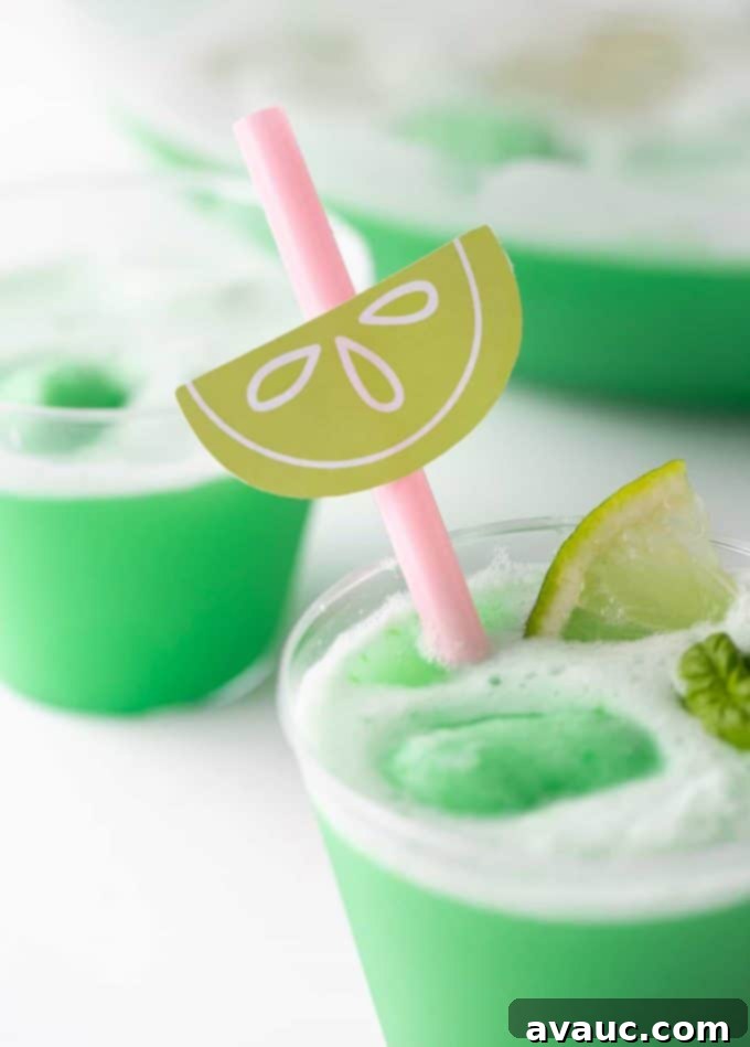 A festive table setting with a punch bowl full of lime sherbet punch, garnished with limes and fresh herbs.