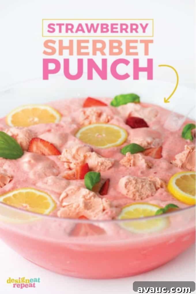 Vibrant Pink Strawberry Sherbet Punch in a large bowl, garnished with fresh strawberries, lemon slices, and basil leaves.