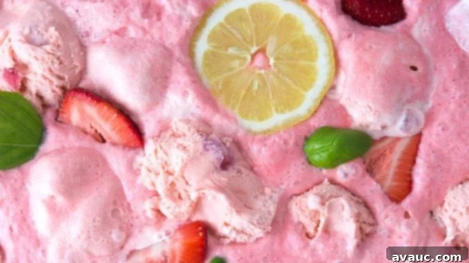 Overhead view of a vibrant pink punch with frothy sherbet scoops, ready for serving.