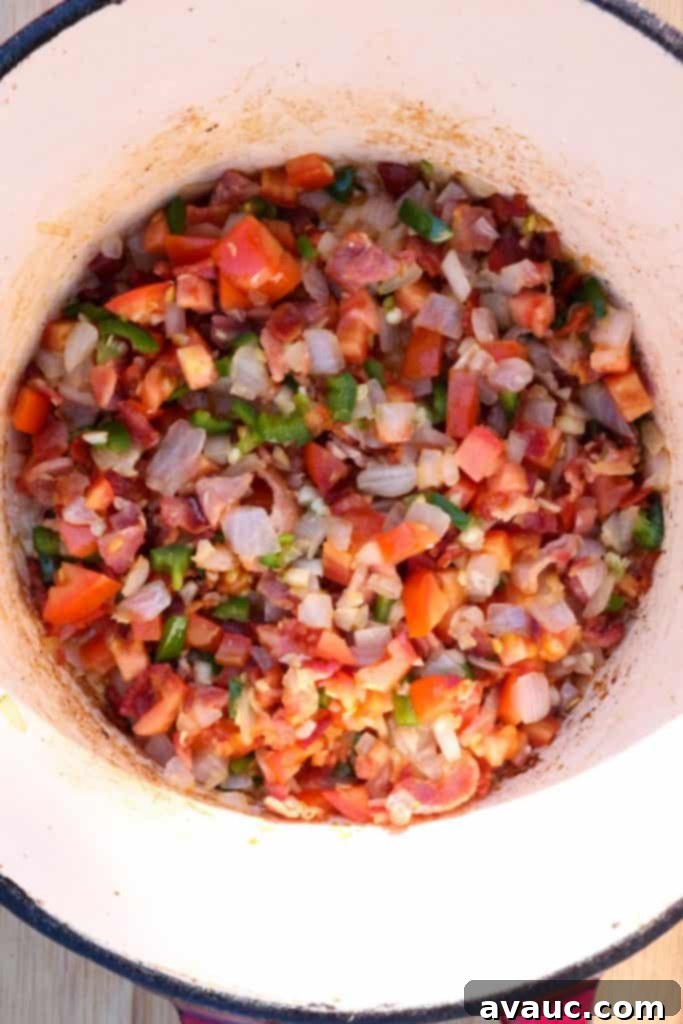 A small pot containing diced bacon, jalapeño, tomato, onion, and garlic, ready to be sautéed for the lentil soup base.