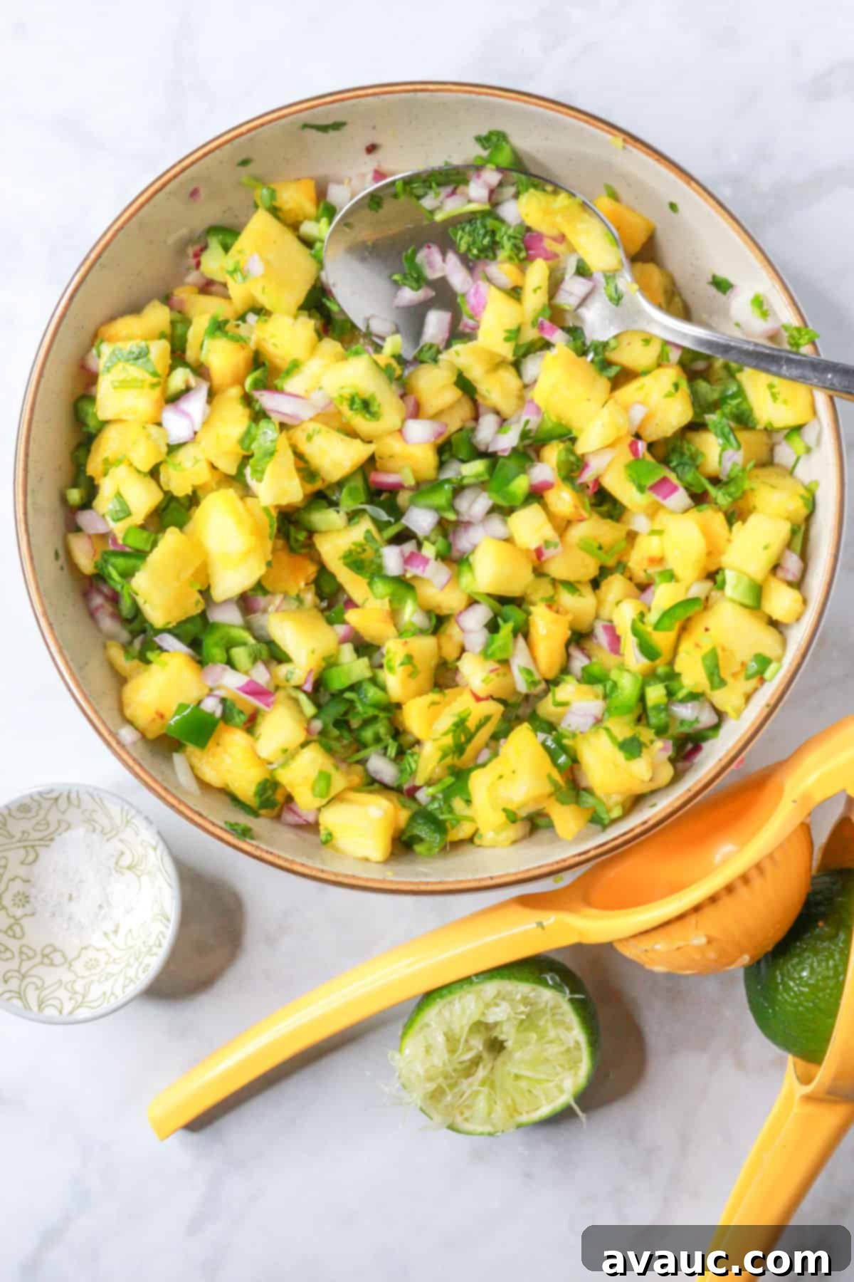 Sweet Heat Pineapple Jalapeño Salsa 8 Mixed pineapple salsa in a bowl with a small bowl of salt and squeezed limes beside it