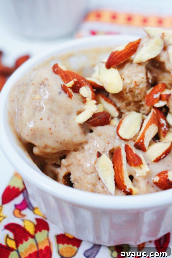 A bowl of delicious No-Churn Banana-Almond Butter Ice Cream topped with toasted almond slices and a spoon.