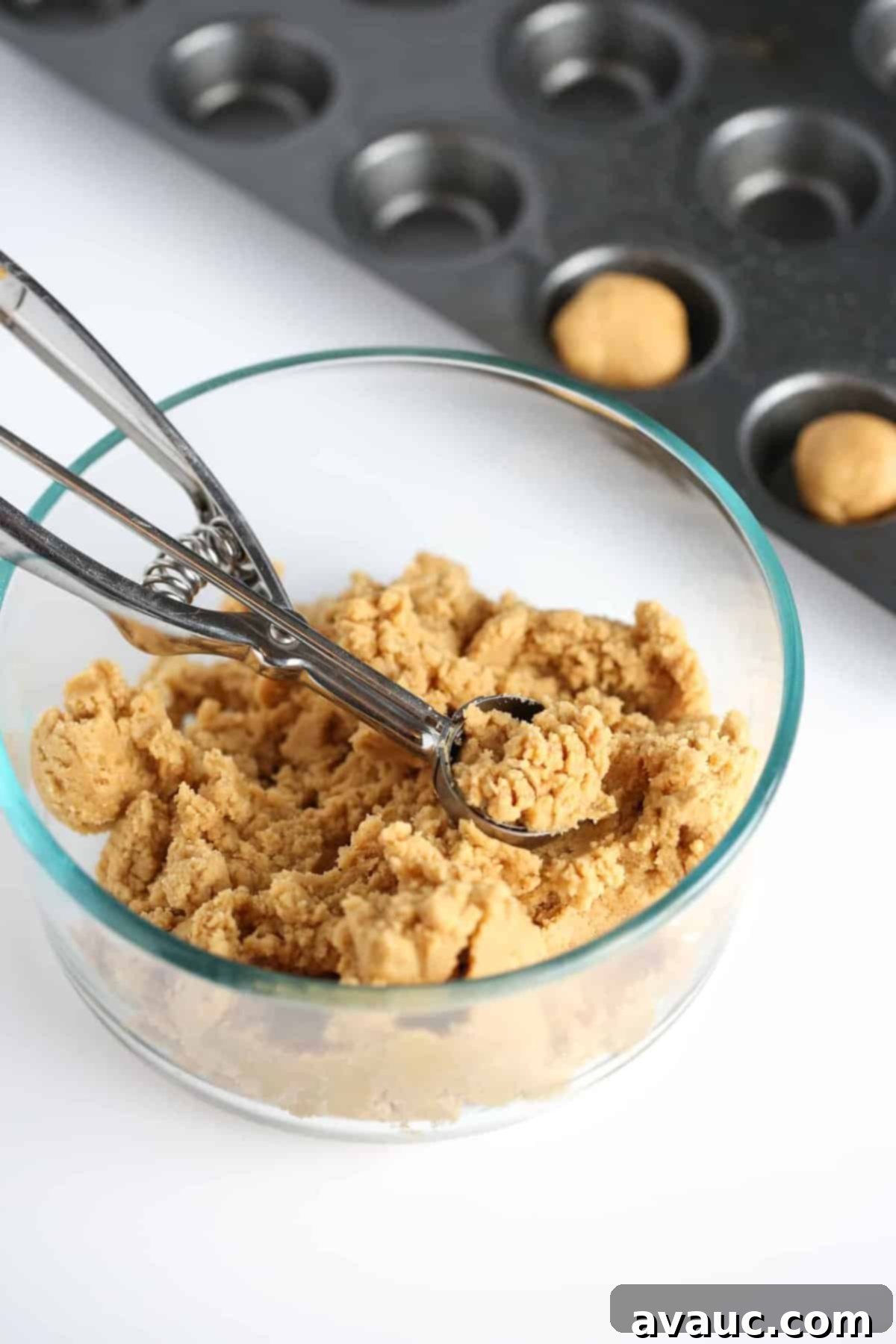 A bowl filled with peanut butter cookie dough, ready to be scooped and baked into delicious cookie cups.