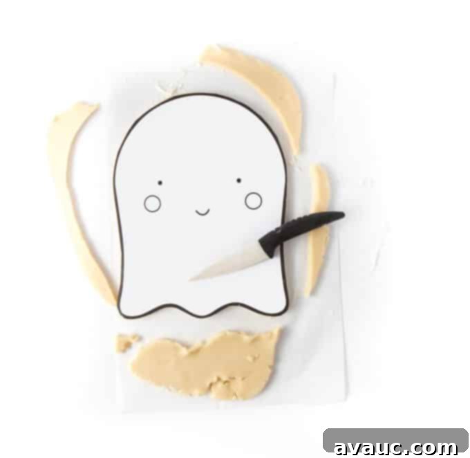 Carefully cutting the ghost shape out of sugar cookie dough using a knife and a printable template