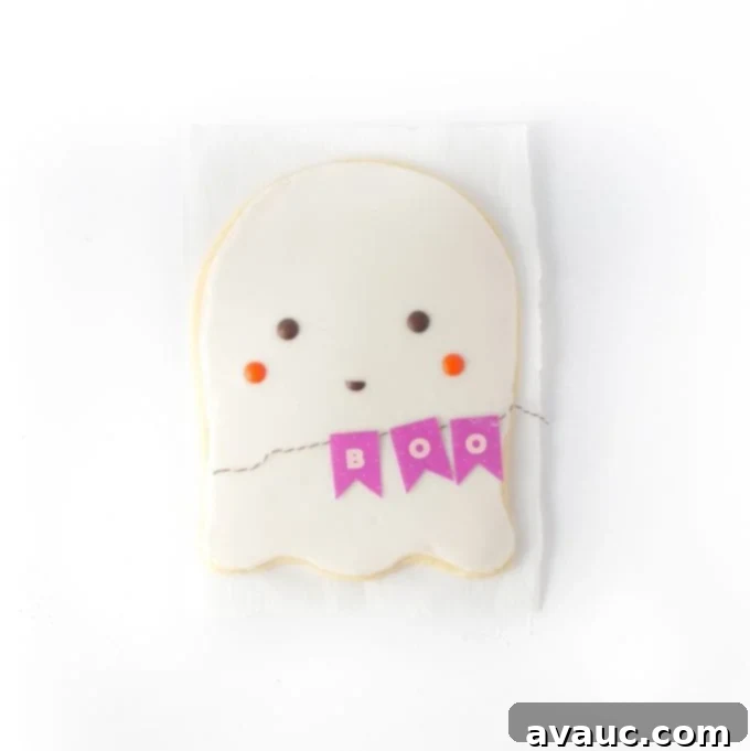 Decorating a giant ghost sugar cookie with M&M's for eyes and cheeks, and a cut M&M for the mouth, with a 'Boo' banner