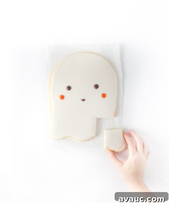 Hand reaching in for a square of giant ghost sugar cookie cake, a perfect Halloween dessert