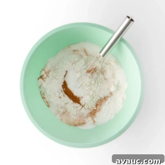 Mixing dry ingredients in a large bowl with a whisk for pumpkin cupcakes.