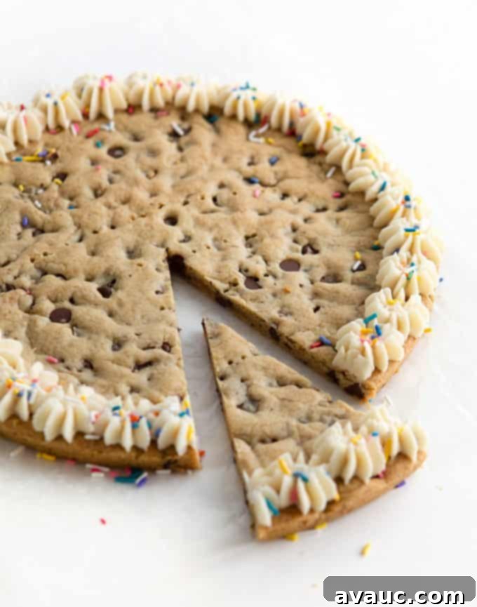 A slice of homemade cookie cake with frosting and sprinkles on a plate