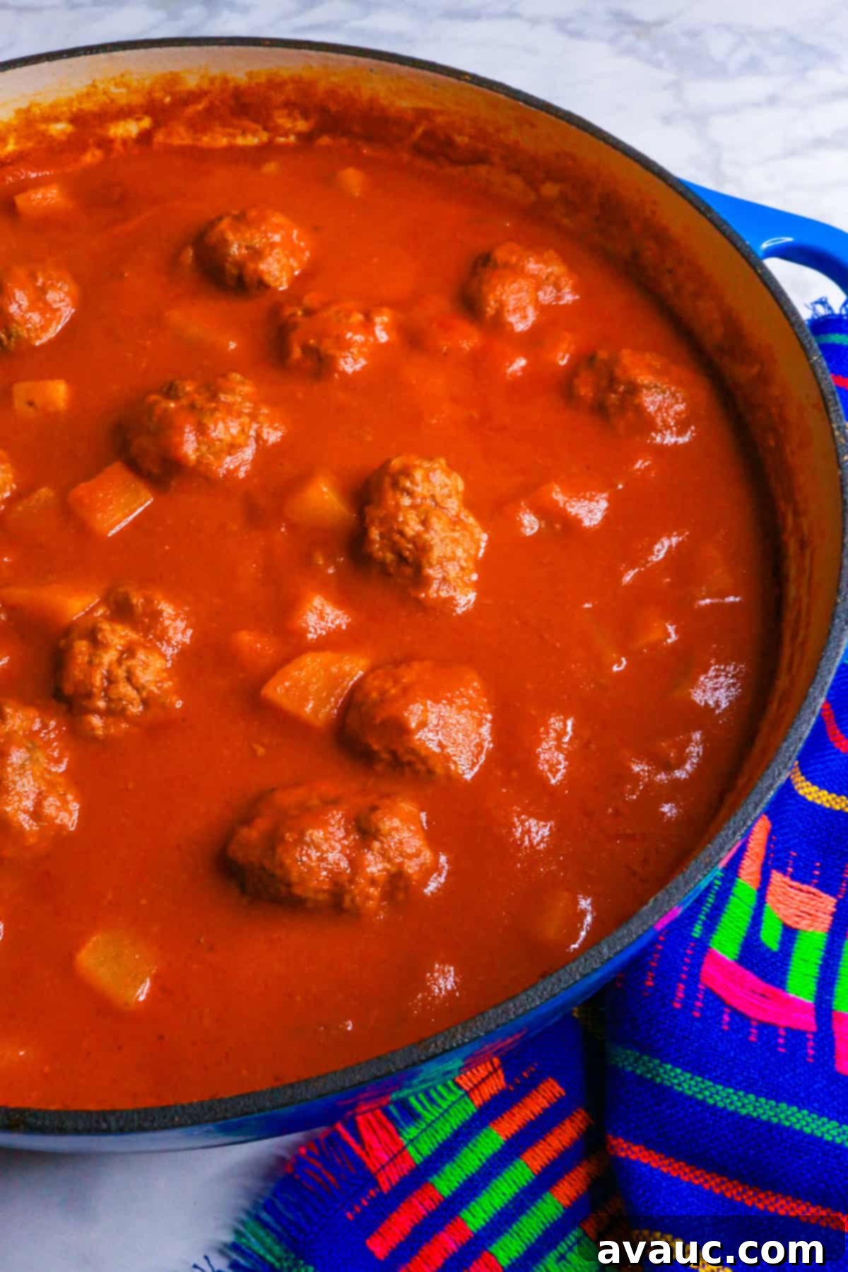 Albondigas in chipotle sauce simmering in a large pot, steam rising, indicating a freshly cooked, comforting meal.