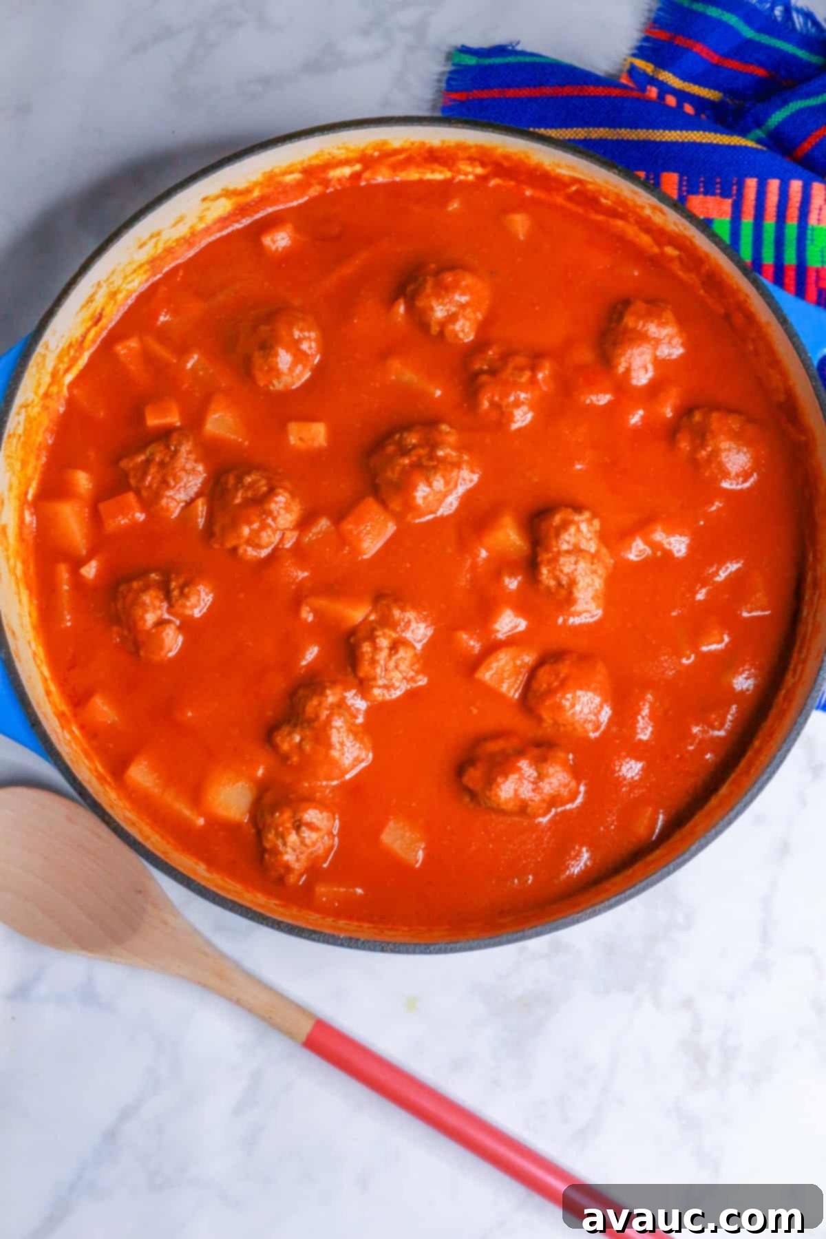 Overhead view of Albondigas in Chipotle Sauce simmering in a pot, showcasing the rich, red sauce and tender meatballs.