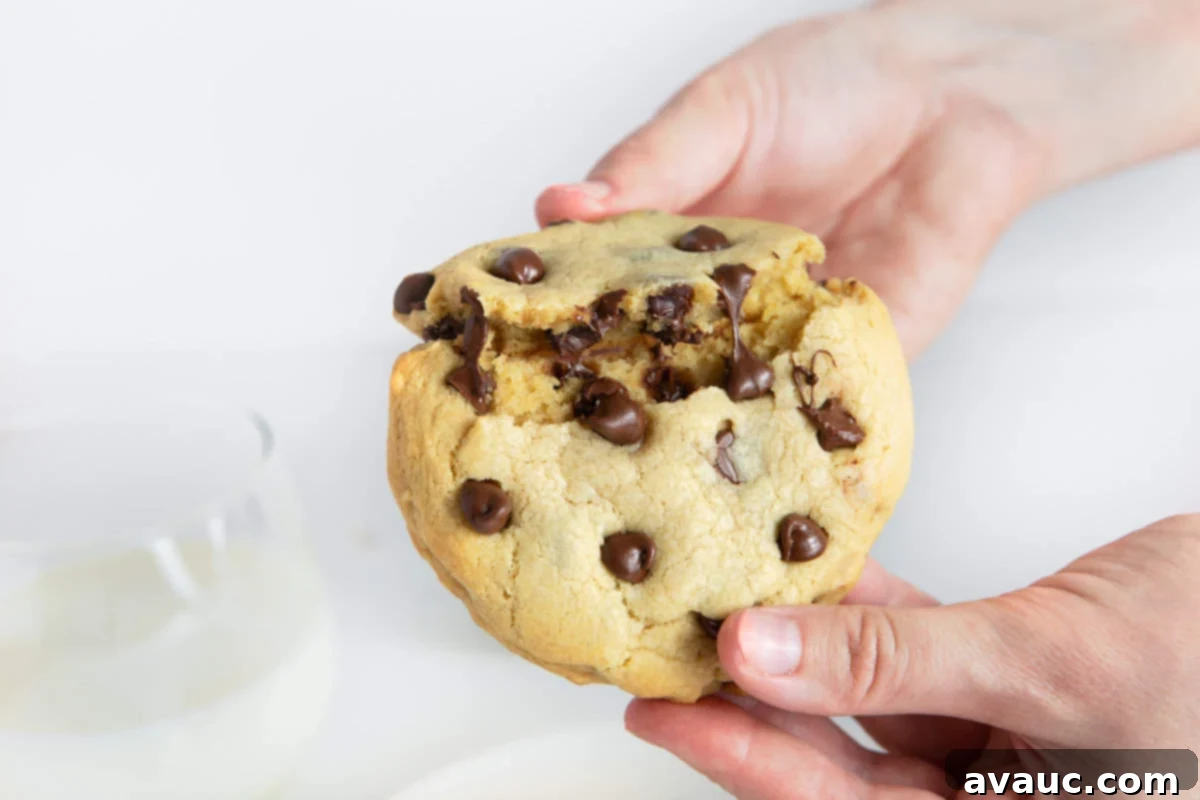 Hand breaking open melty & gooey chocolate chip cookie