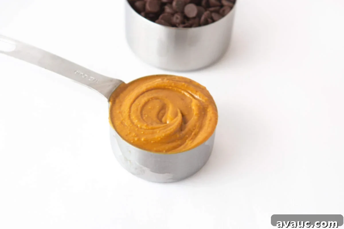 Half cup of natural peanut butter being added to a mixing bowl