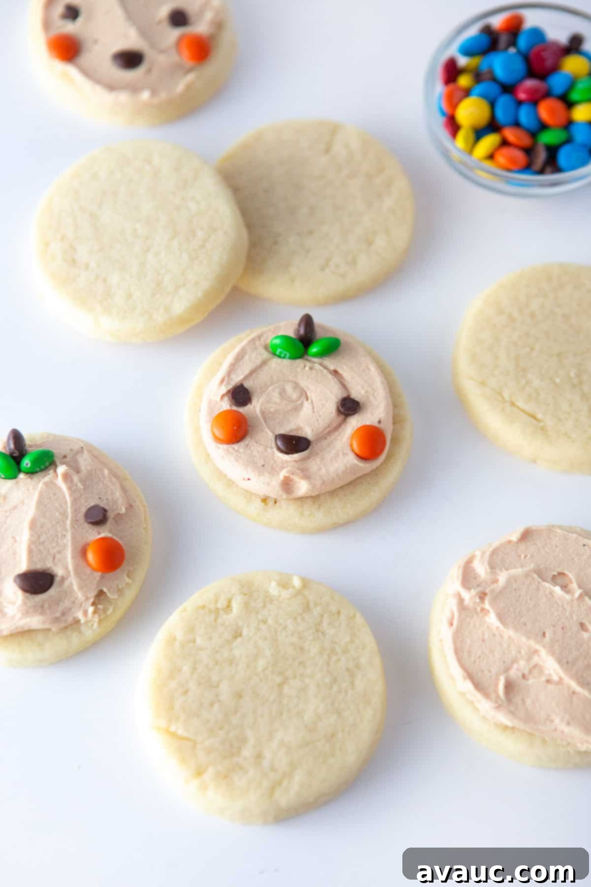 Spooktacularly Simple Pumpkin Cookies 4 Ingredients laid out for easy Halloween pumpkin cookies: sugar cookie dough, orange frosting, mini M&M's, mini chocolate chips, and a circle cookie cutter