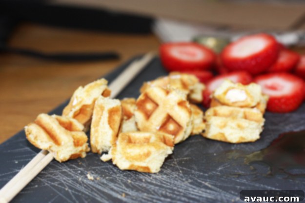Close-up of a waffle kabob showing the alternating layers of waffle and strawberry, with syrup.