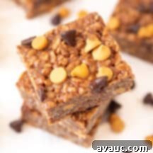A close-up of a stack of three Microwave Scotcheroo bars, showing the rich texture and topping.