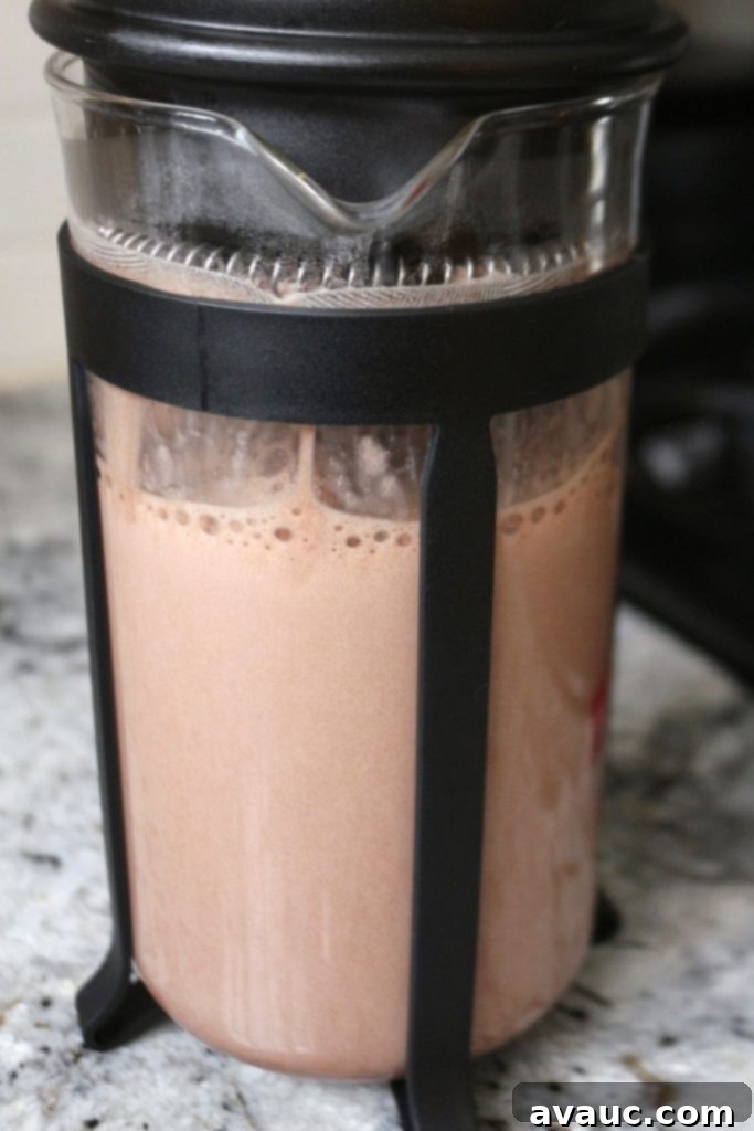 Cocoa Espresso Bliss 6 Frothing dairy-free chocolate milk in a French press for a frothy mocha