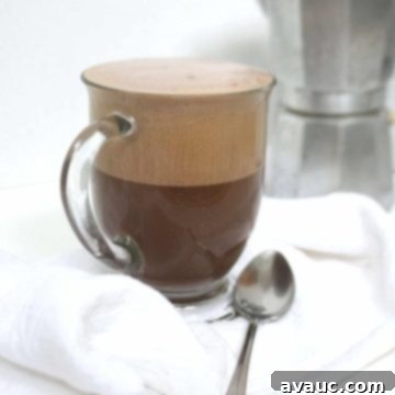 Cocoa Espresso Bliss 10 Mocha latte in a clear mug with a moka pot in the background