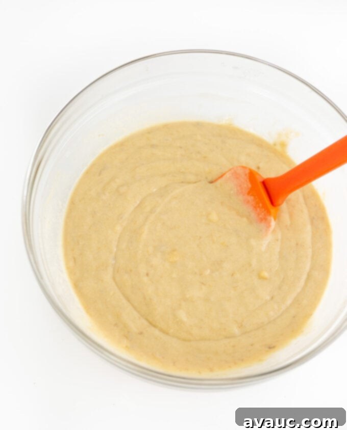 Bowl of banana cake batter with orange spatula