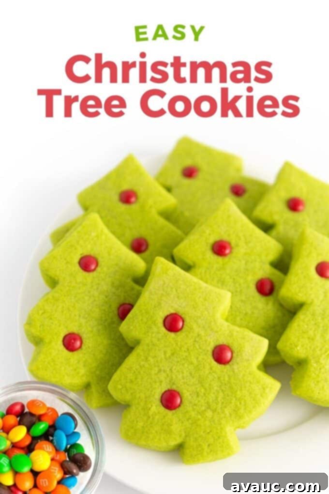 Effortless Christmas Tree Cookies 2 Plate of vibrant green Christmas tree sugar cookies adorned with mini red M&M ornaments, resting on a white plate, ready to be enjoyed during the holidays.