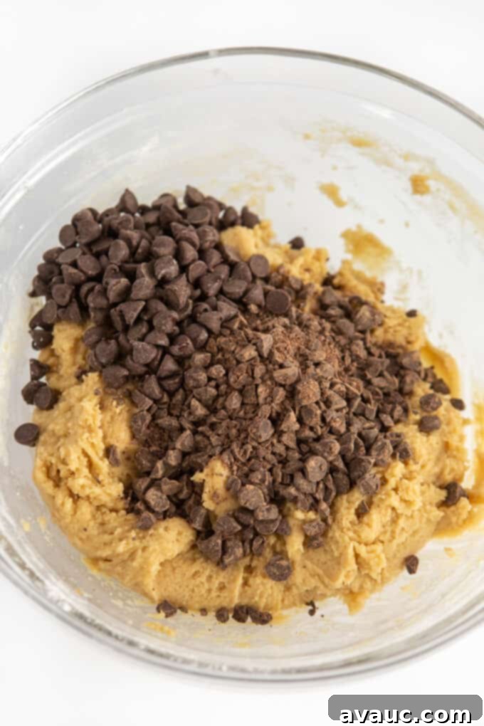 Irresistible Chocolate Chip Squares 7 Raw chocolate chip cookie dough being mixed in a bowl with a spatula.