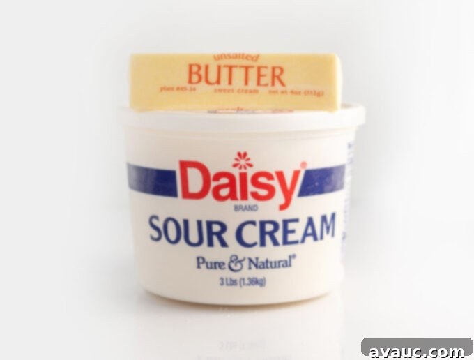 Container of sour cream next to a stick of butter, key ingredients for fluffy sugar cookies