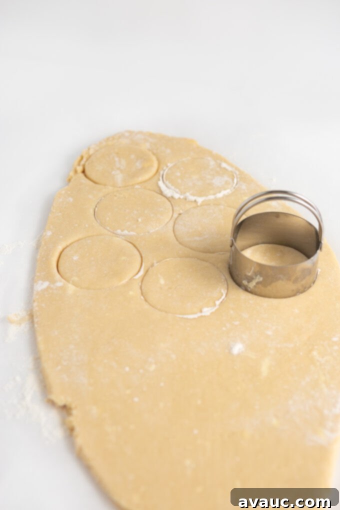 Child-friendly hands cutting out sugar cookie dough with a round cookie cutter