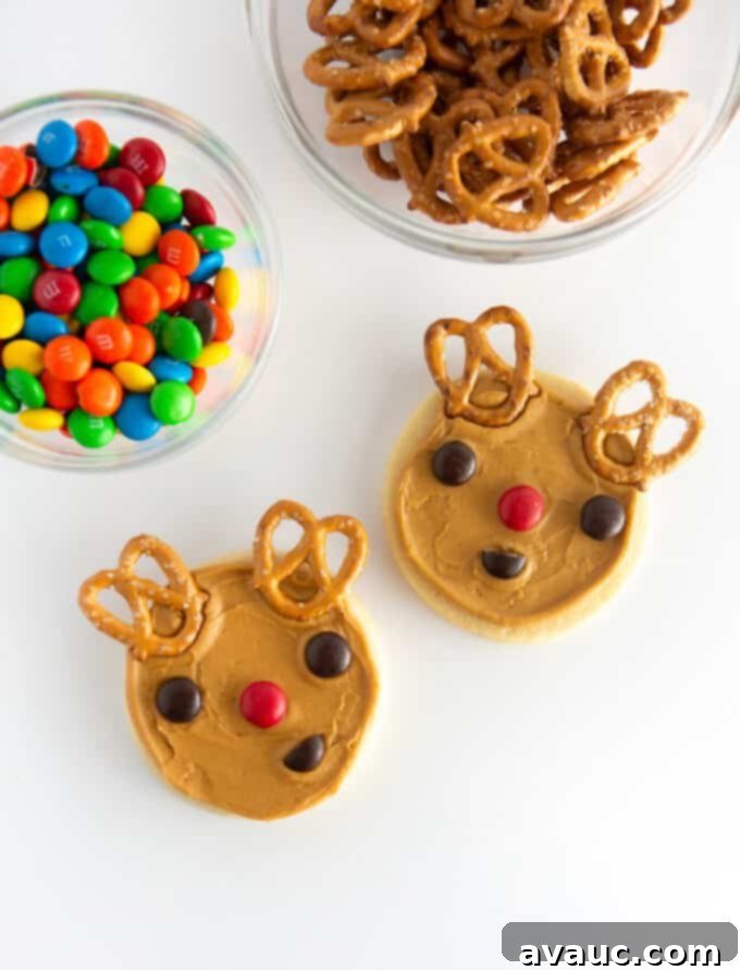 Brown reindeer cookies decorated with M&M eyes, a red M&M nose, and pretzel antlers