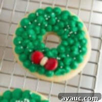 Close-up of a festive green wreath sugar cookie decorated with red M&Ms