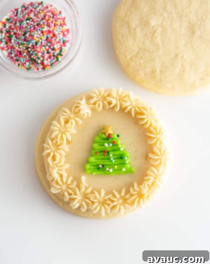 white sugar cookie decorated with a green piped Christmas tree and sprinkles in the center