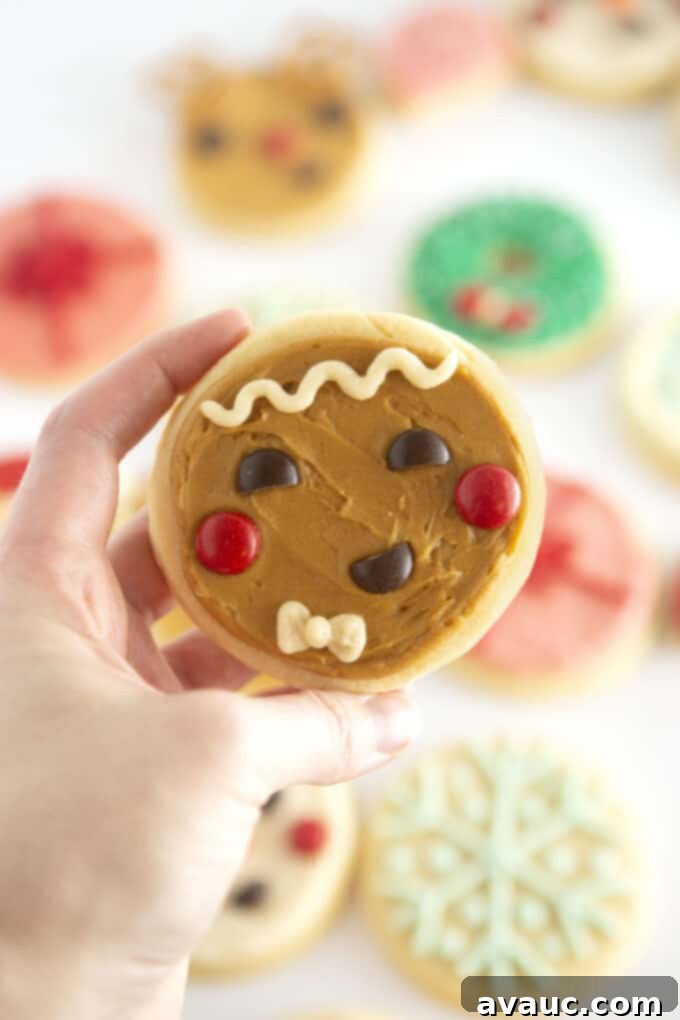 Round Gingerbread Man Sugar Cookies 3 Hand holding a finished brown gingerbread man face cookie with M&M eyes and cheeks.