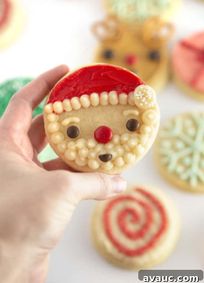 Hand holding circle Santa face sugar cookies decorated with M&M candy