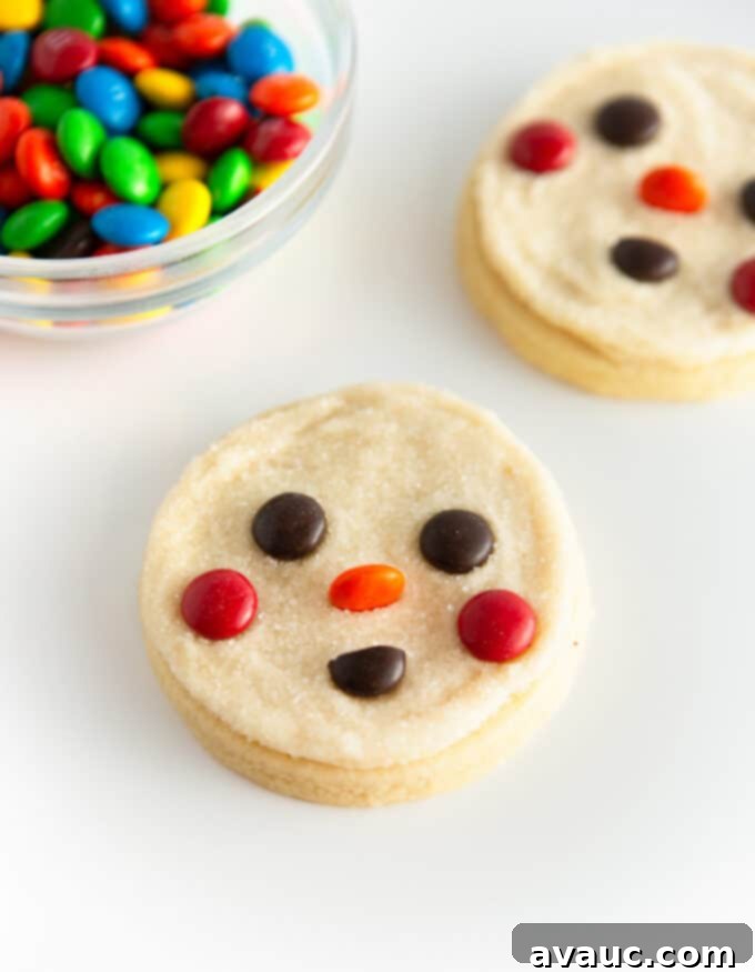 5 Easy Winter Cookie Recipes 5 A cute round snowman cookie with rosy M&M cheeks, an orange M&M nose, and a half M&M smile, dusted with white sanding sugar.