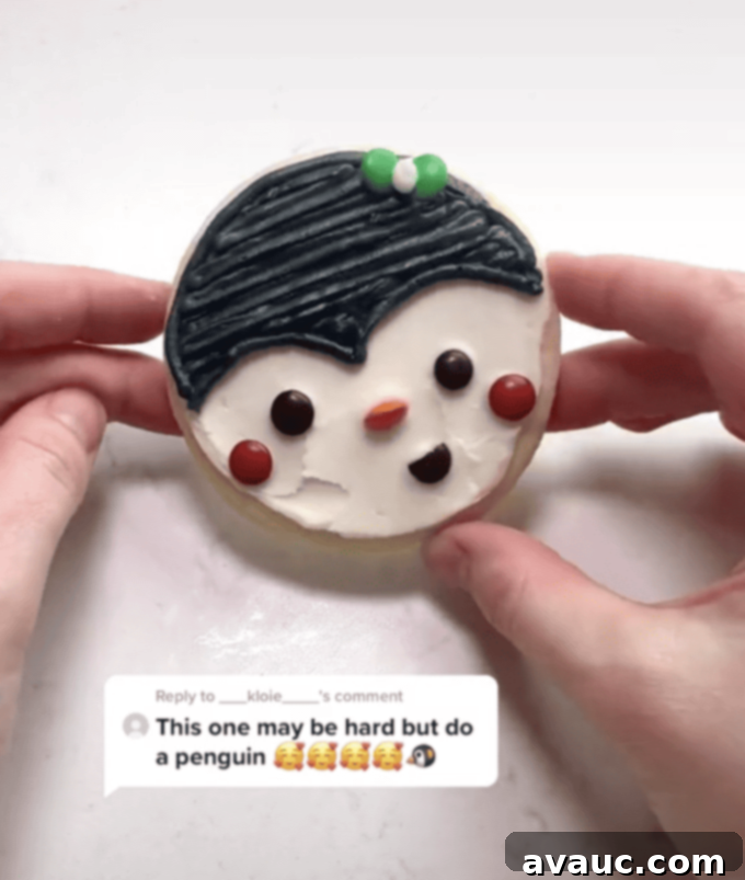 5 Easy Winter Cookie Recipes 7 An adorable round penguin cookie with white and black frosting, mini M&M eyes and cheeks, an orange M&M beak, and a green M&M bow tie.